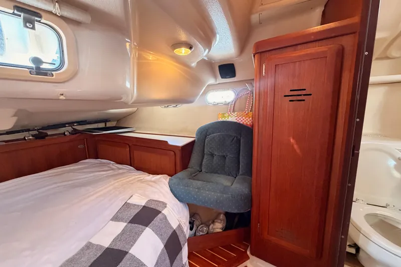 Slide: The Image of Cozy cabin interior of a 1997 Hunter 430 sailboat with bed, chair, and wooden cabinetry. - 76