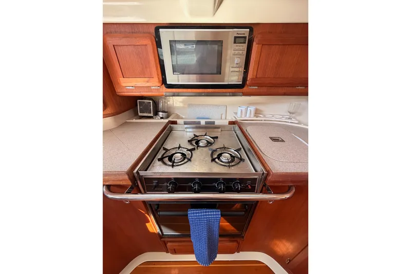 Slide: The Image of Galley kitchen in 1997 Hunter 430 yacht with stove, microwave, and wooden cabinetry. - 45