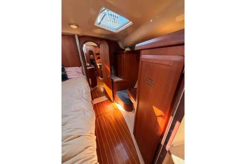 Slide: The Image of Interior of a 1997 Hunter 430 sailboat with wooden cabinetry and cozy sleeping area. - 62