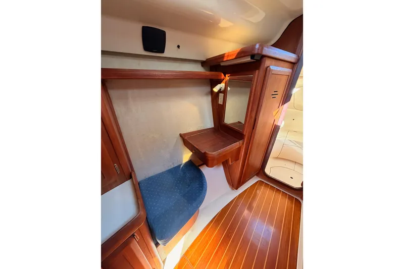 Slide: The Image of Interior of a 1997 Hunter 430 sailboat featuring wooden cabinetry and blue cushioned seating. - 55