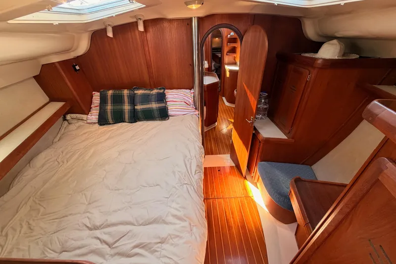 Slide: The Image of Cozy cabin interior of a 1997 Hunter 430 sailboat with wooden furnishings and a comfortable bed. - 64