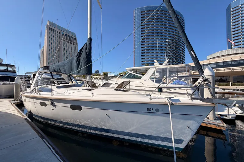 Slide: The Image of 1997 Hunter 430 sailboat docked in marina with modern buildings in background. - 1