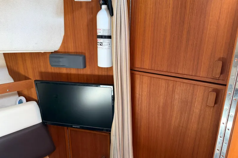 Slide: The Image of Interior of 2017 Ranger Tugs R-31 S with TV, fire extinguisher, and wooden cabinetry. - 43