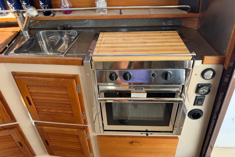 Slide: The Image of 2017 Ranger Tugs R-31 S galley with sink, stove, and wooden cabinetry. - 13