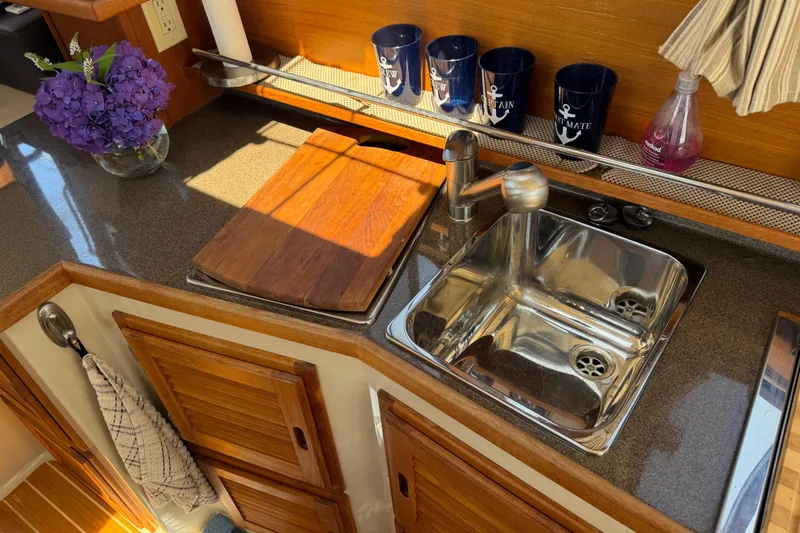 Slide: The Image of Cozy kitchen area in a 2017 Ranger Tugs R-31 S boat with sink and wooden cabinets. - 15