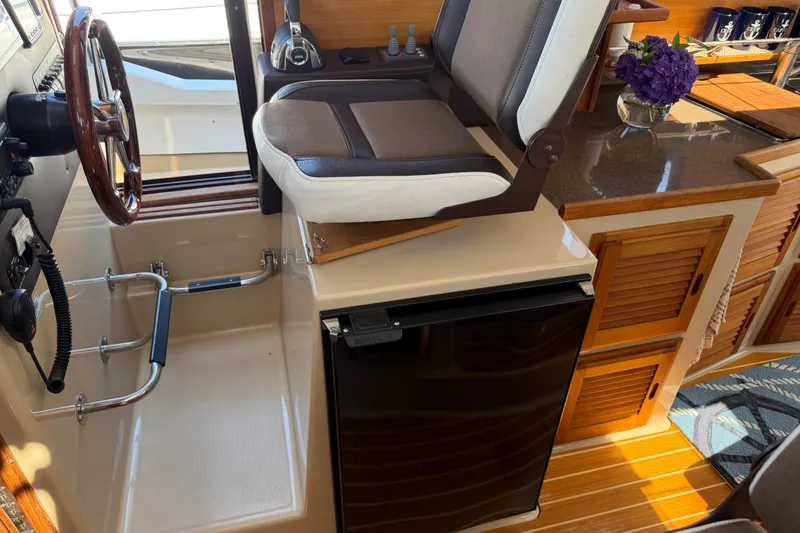 Slide: The Image of Interior of 2017 Ranger Tugs R-31 S with helm seat, steering wheel, and compact fridge. - 24