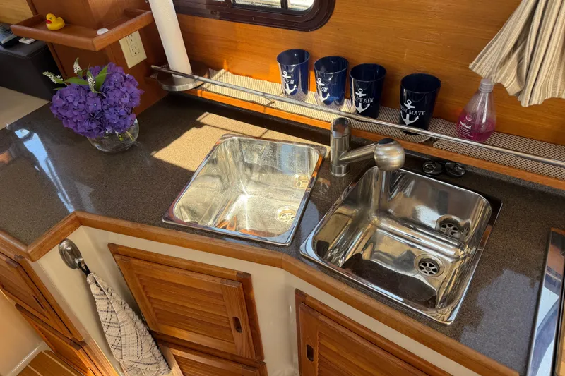 Slide: The Image of 2017 Ranger Tugs R-31 S kitchen with dual sinks, wooden cabinets, and decorative elements. - 16