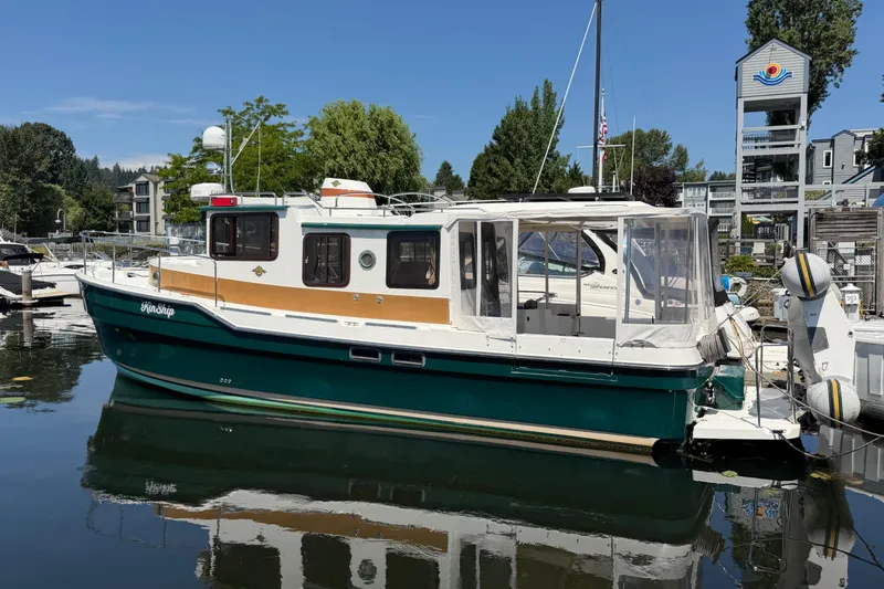 Slide: The Image of 2017 Ranger Tugs R-31 S boat docked in a marina, surrounded by trees and buildings. - 1