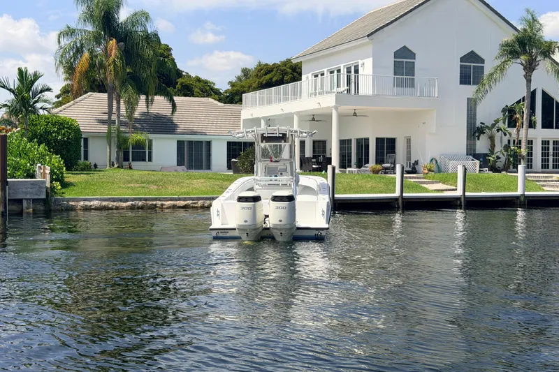 Slide: The Image of 2006 Contender 31 Open boat docked by a waterfront house with palm trees. - 11