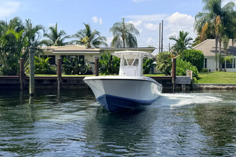 Slide: The Image of 2006 Contender 31 Open boat cruising near a waterfront home with lush palm trees. - 3