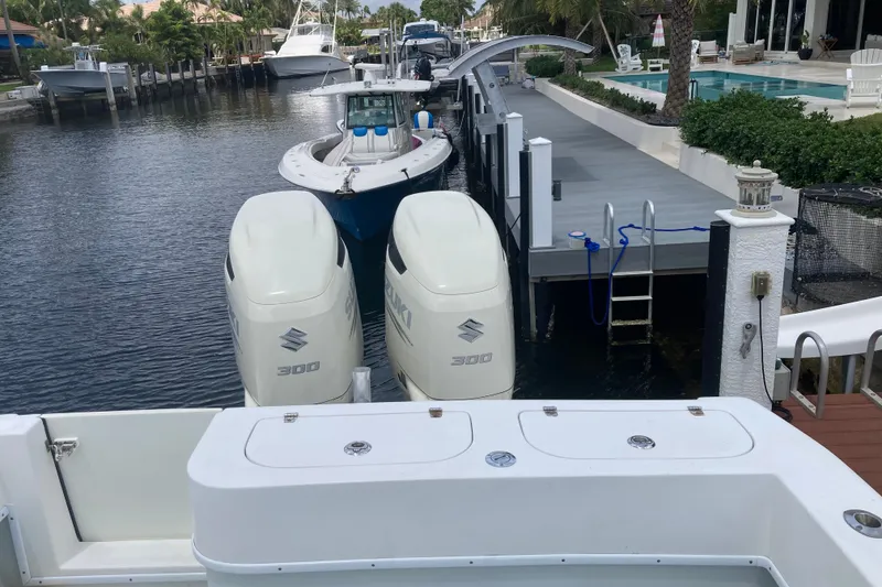 Slide: The Image of 2006 Contender 31 Open boat with twin Suzuki 300 engines docked by waterfront homes. - 32