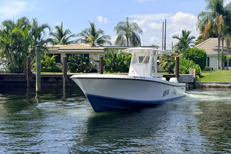 Slide: The Image of 2006 Contender 31 Open boat cruising near waterfront homes with lush palm trees. - 2