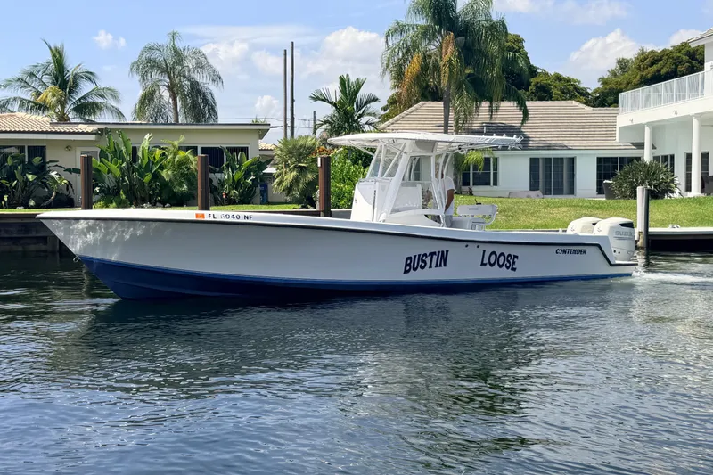 Slide: The Image of 2006 Contender 31 Open boat named "Bustin Loose" docked by waterfront homes. - 13