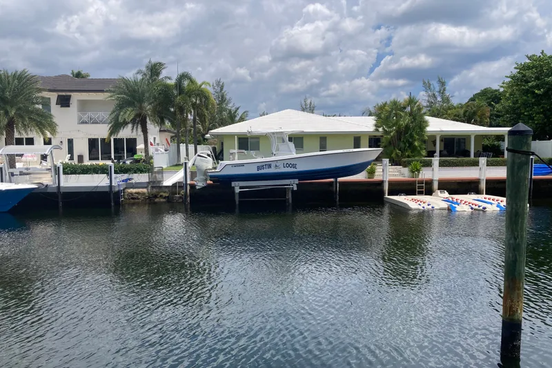 Slide: The Image of 2006 Contender 31 Open boat docked by waterfront homes under cloudy sky. - 1