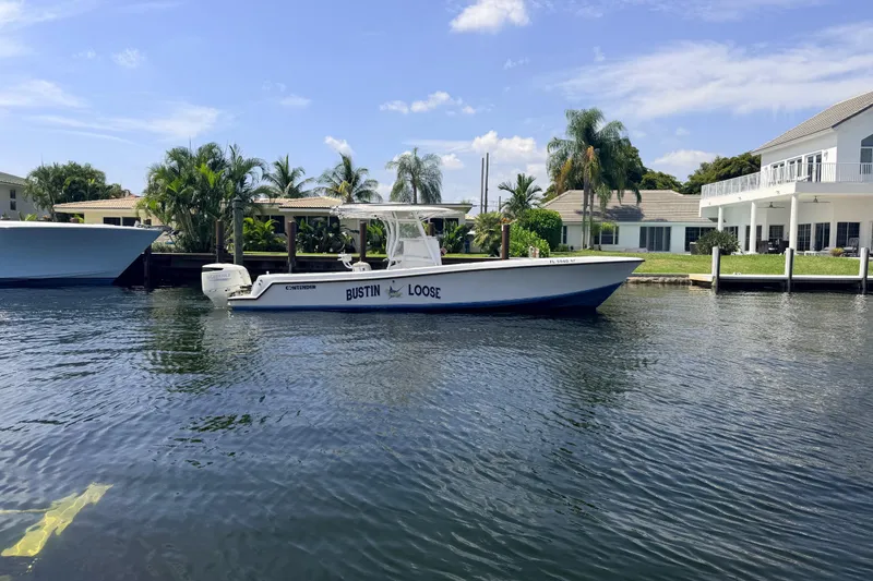 Slide: The Image of 2006 Contender 31 Open boat docked by waterfront homes, surrounded by palm trees. - 8