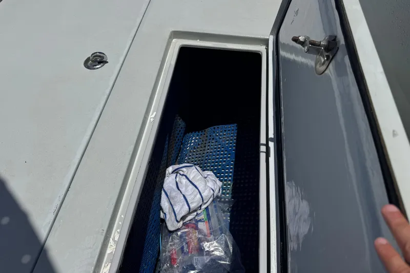 Slide: The Image of Open storage compartment on a 2006 Contender 31 Open boat, containing a towel and plastic bag. - 23
