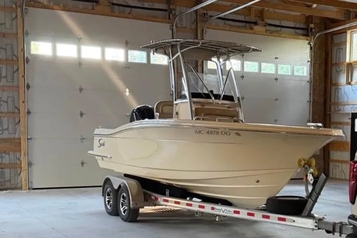 Slide: The Image of 2019 Scout 215 XSF boat on trailer in a garage setting. - 2