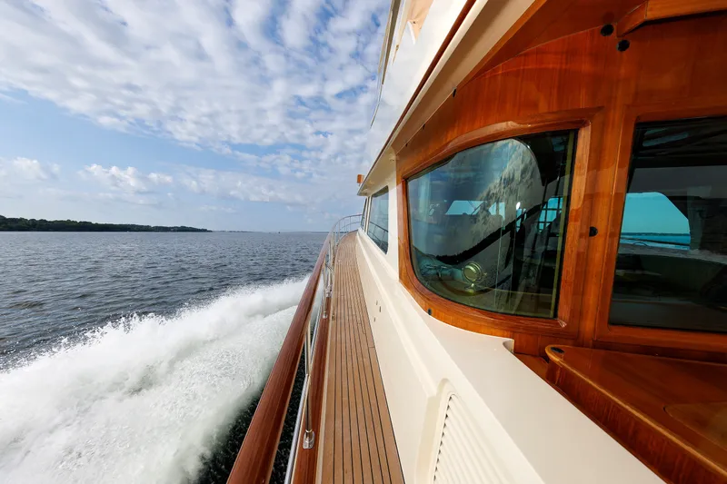 Slide: The Image of 2016 Hunt Yachts 72 FB cruising on open water, showcasing sleek wooden deck and windows. - 58