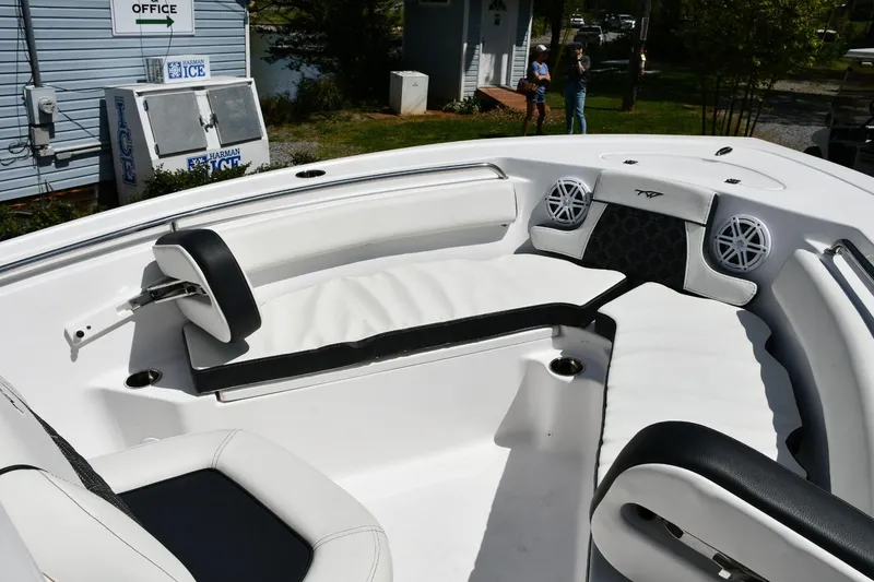 Slide: The Image of 2023 Tidewater 210 LXF boat interior with white seating and speakers, dockside view. - 11