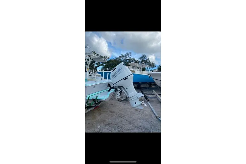 Slide: The Image of 2026 Exuma 22 boat with Suzuki outboard motor, parked outdoors under cloudy sky. - 5