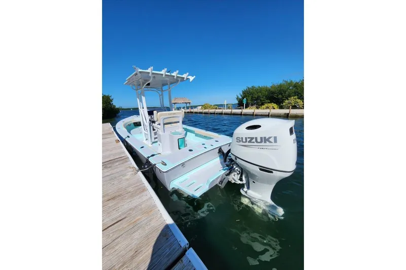 Slide: The Image of 2026 Exuma 22 boat with Suzuki outboard motor docked on a sunny day. - 2