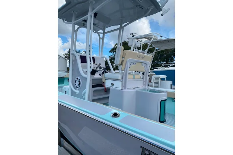 Slide: The Image of 2026 Exuma 22 boat interior with modern helm and seating, under a clear blue sky. - 4