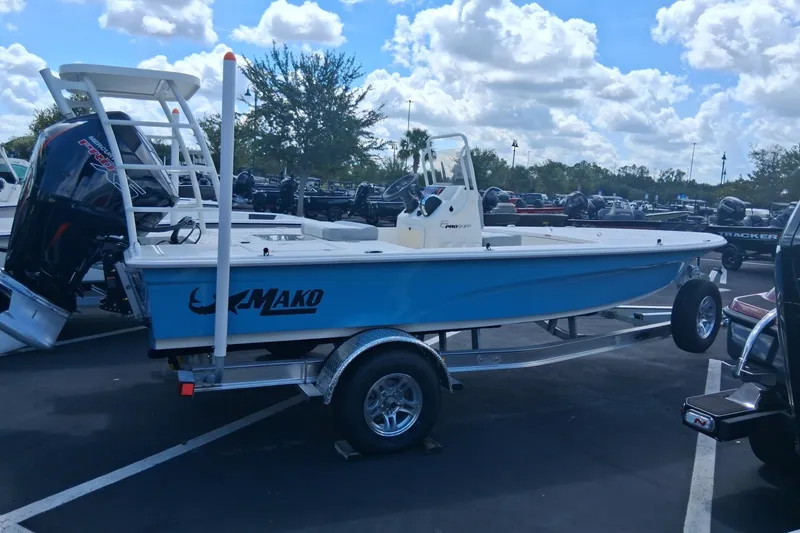 Slide: The Image of 2026 Mako 18 Pro Skiff boat on trailer in parking lot under cloudy sky. - 1