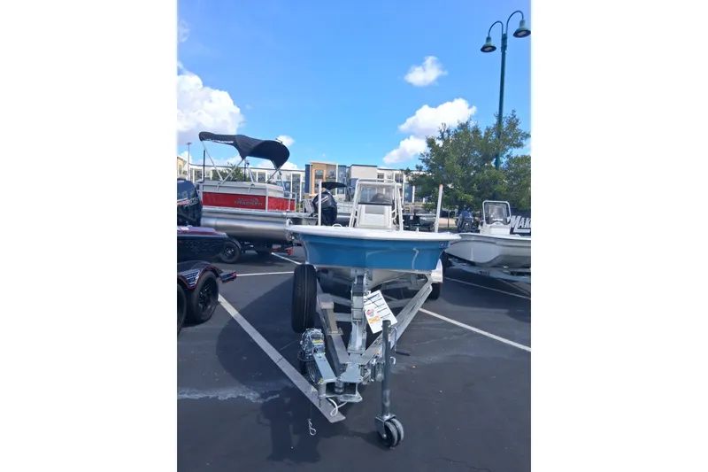 Slide: The Image of 2026 Mako 18 Pro Skiff boat on trailer in parking lot under blue sky. - 2