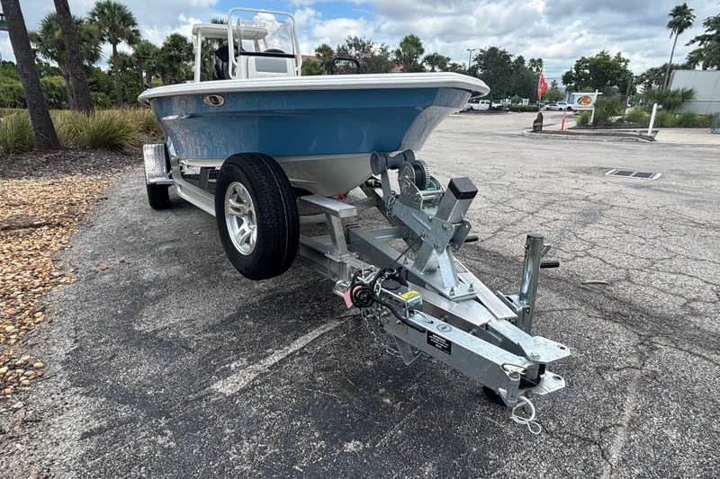Slide: The Image of 2026 Mako 18 Pro Skiff boat on trailer in parking lot, surrounded by palm trees. - 6