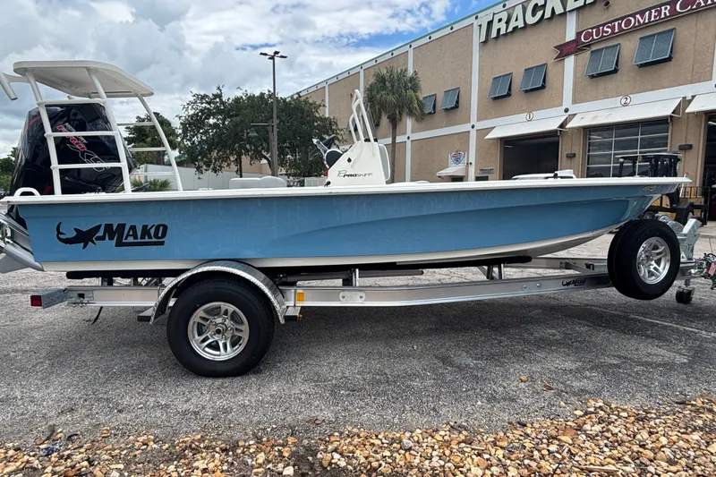 Slide: The Image of 2026 Mako 18 Pro Skiff boat on trailer, parked outside a dealership. - 4