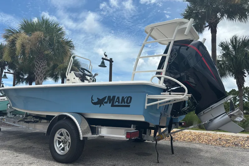 Slide: The Image of 2026 Mako 18 Pro Skiff boat on trailer, parked near palm trees under a blue sky. - 2