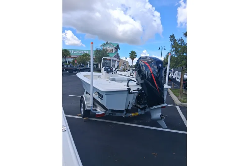 Slide: The Image of 2026 Mako 18 Pro Skiff boat on trailer in parking lot under blue sky. - 2