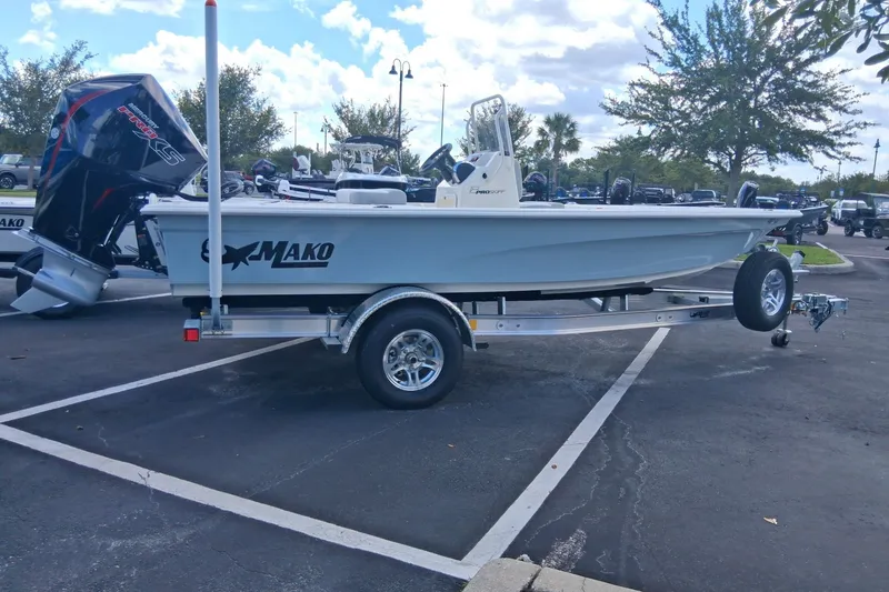 Slide: The Image of 2026 Mako 18 Pro Skiff boat on trailer in parking lot, under cloudy sky. - 1