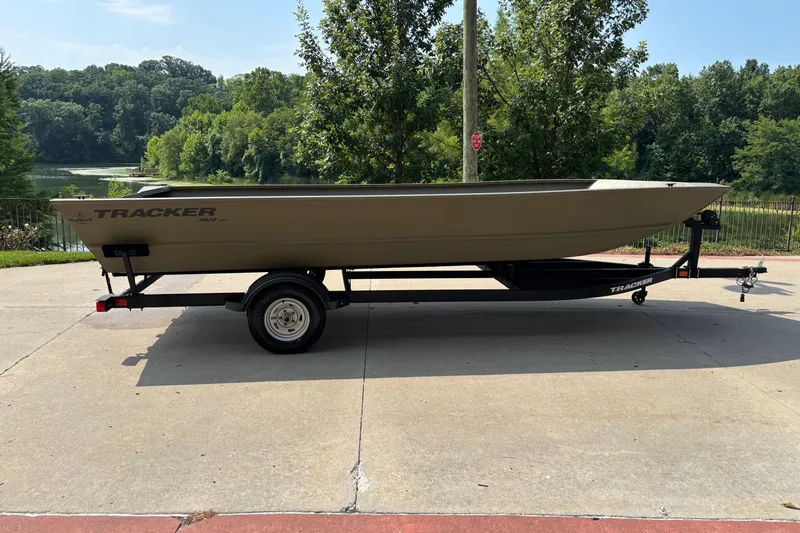 The Image of 2026 Tracker Grizzly 2072 Utility boat on trailer, parked outdoors near lush greenery. - 0