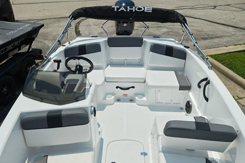 Slide: The Image of 2026 Tahoe T16 boat interior with seating, steering wheel, and windshield, parked on pavement. - 20