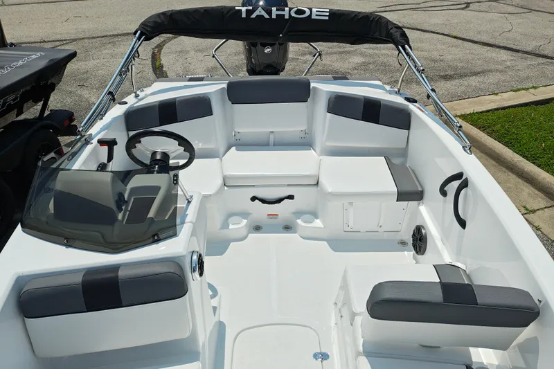 Slide: The Image of 2026 Tahoe T16 boat interior with seating, steering wheel, and windshield, parked on pavement. - 4