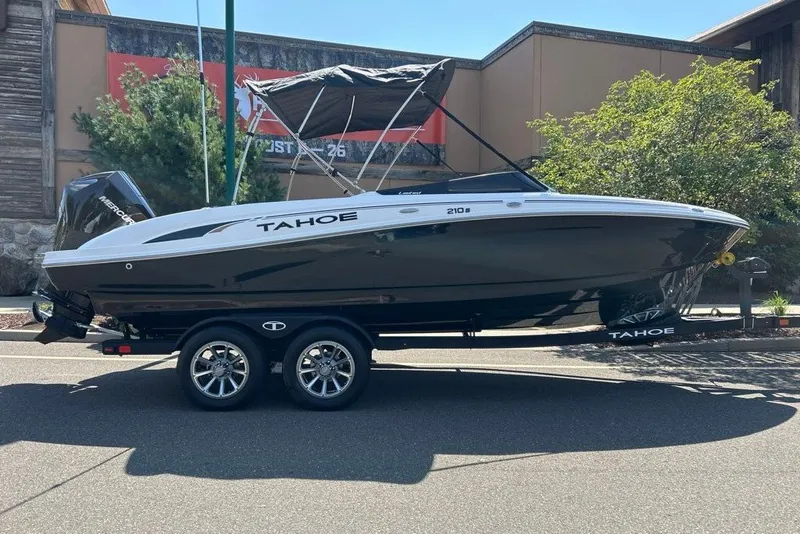 The Image of 2026 Tahoe 210 S boat on trailer, parked outdoors with canopy. - 0