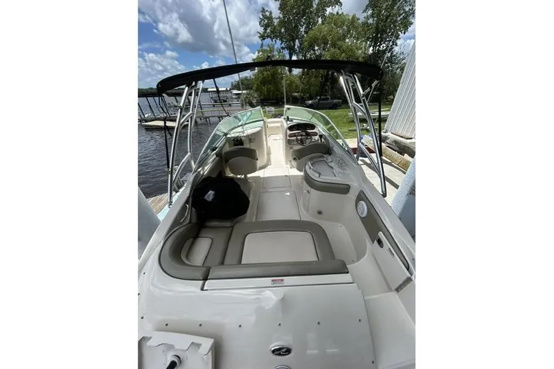 Slide: The Image of 2005 Sea Ray 270 Sundeck boat interior with seating, docked by a lake under a cloudy sky. - 8