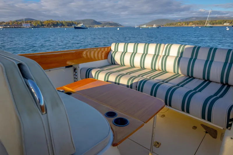 Slide: The Image of 2001 Hinckley Picnic Boat 36 Classic with striped seating, scenic waterfront view. - 21