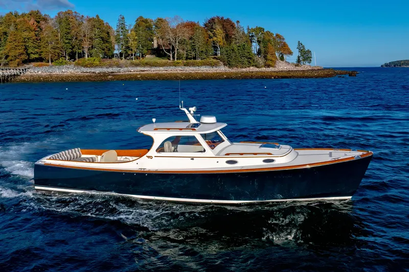 Slide: The Image of 2001 Hinckley Picnic Boat 36 Classic cruising on blue waters near a wooded shoreline. - 4