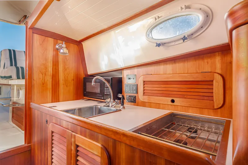 Slide: The Image of Interior of 2001 Hinckley Picnic Boat 36 Classic with wooden cabinetry and kitchenette. - 30