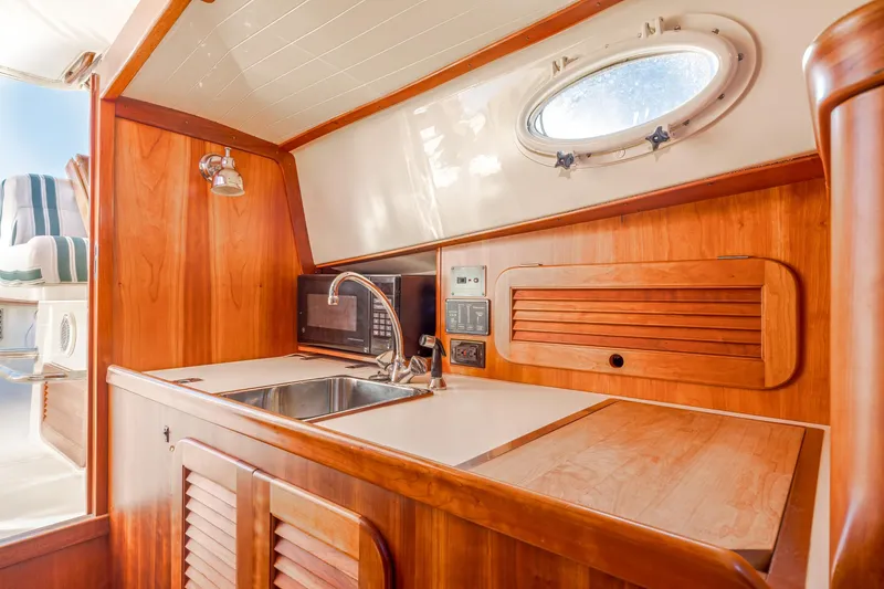 Slide: The Image of Interior of 2001 Hinckley Picnic Boat 36 Classic with wooden cabinetry and kitchenette. - 29