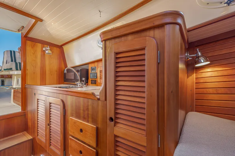 Slide: The Image of 2001 Hinckley Picnic Boat 36 Classic interior with wooden cabinetry and compact kitchen area. - 31