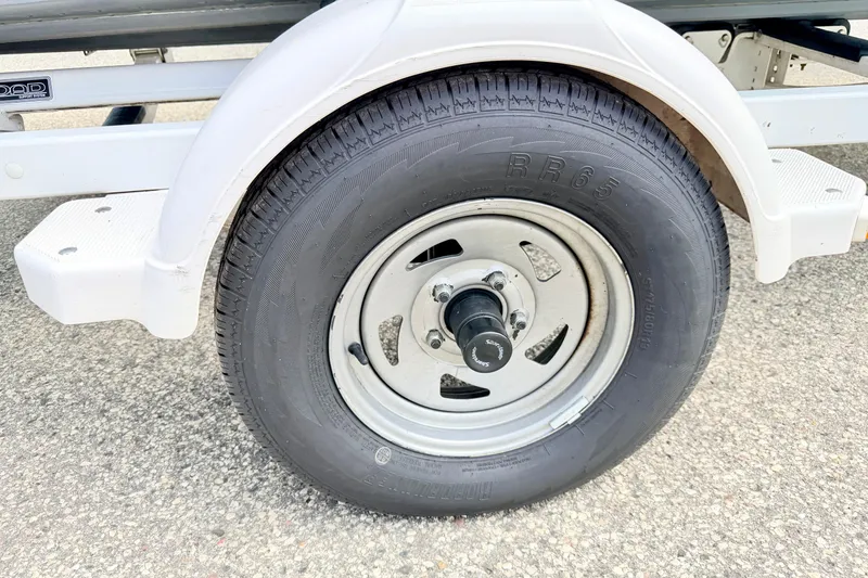 Slide: The Image of Trailer wheel of a 2002 Lund 1650 Rebel SS boat on pavement. - 68