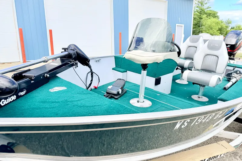 Slide: The Image of 2002 Lund 1650 Rebel SS fishing boat with green carpet and seating, parked outdoors. - 56