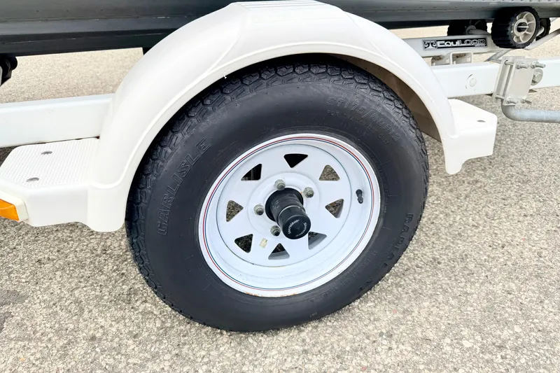 Slide: The Image of Trailer wheel of a 2002 Lund 1650 Rebel SS boat on pavement. - 62