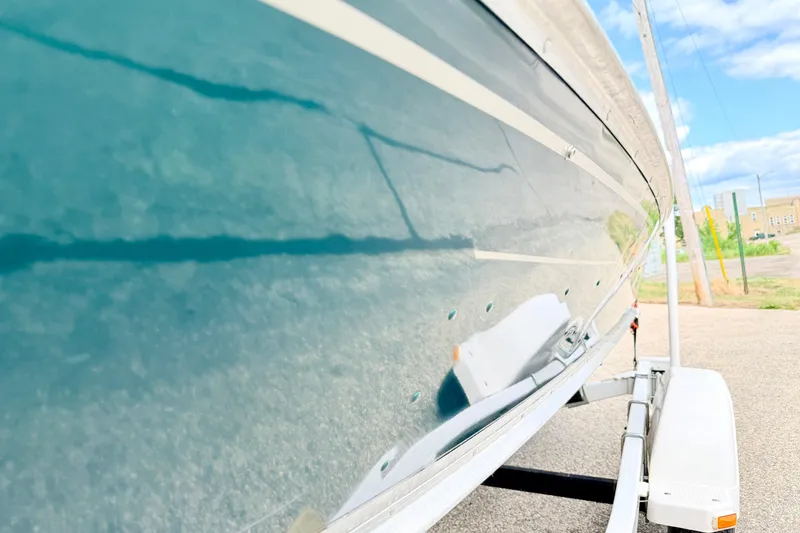 Slide: The Image of 2002 Lund 1650 Rebel SS boat on trailer, reflecting clear sky and surroundings. - 55