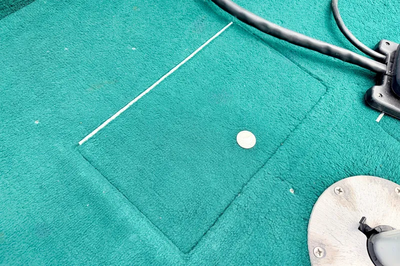 Slide: The Image of Teal carpeted floor of a 2002 Lund 1650 Rebel SS boat with a coin and metal fixture. - 45