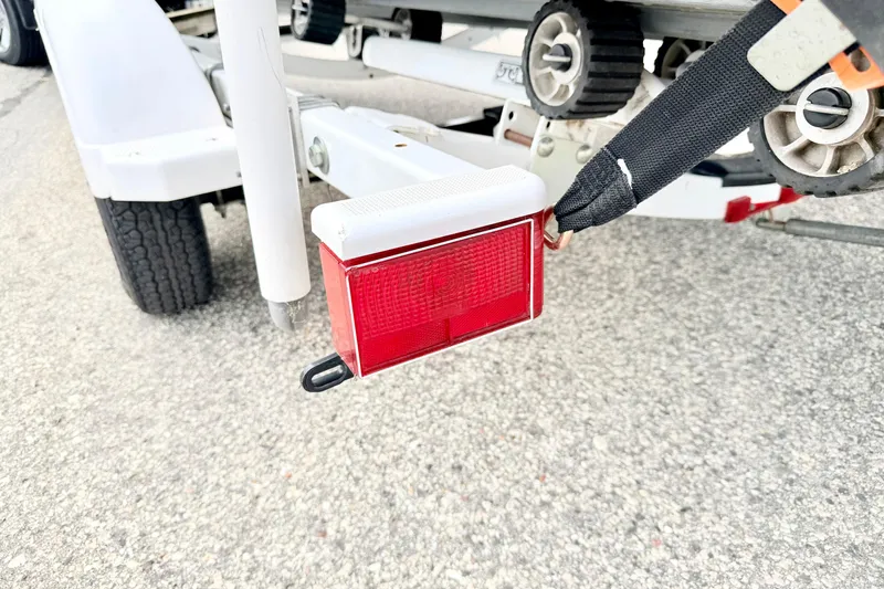 Slide: The Image of Trailer light on a 2002 Lund 1650 Rebel SS boat trailer, showing red reflector and strap. - 64