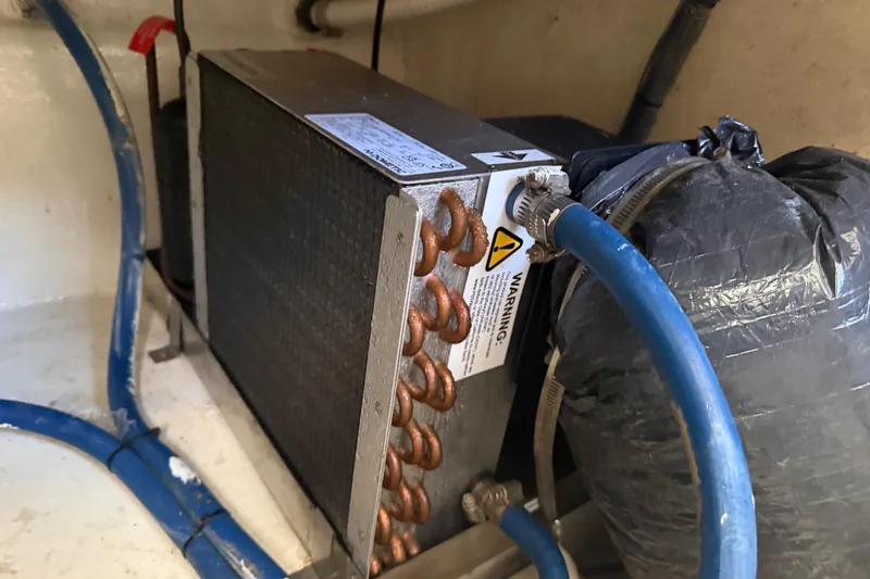 Slide: The Image of Engine room of 2000 Cabo 35 Flybridge with cooling system components and blue hoses. - 101